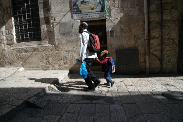 A father walking with his son, to school perhaps.